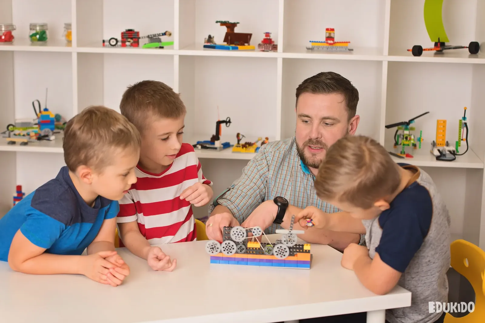 Instruktor i trzej chłopcy oglądają model z kołami zębatymi