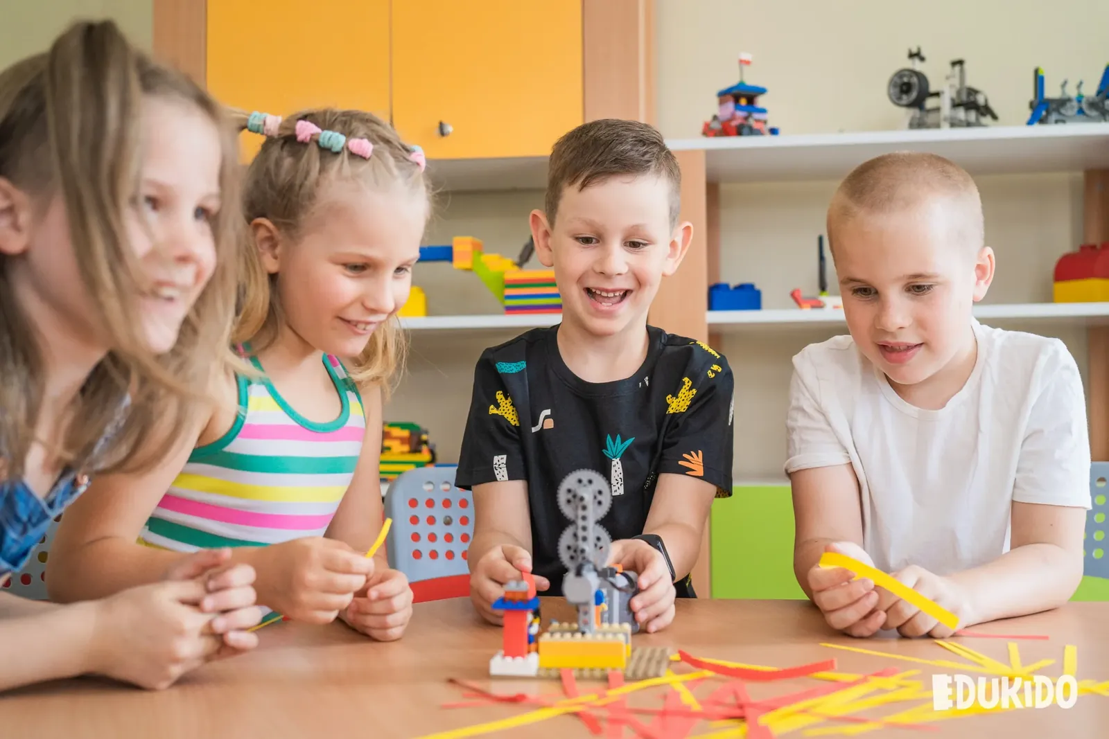 Czworo dzieci przy stole ogląda zbudowany model z przekładniami